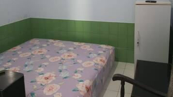 Una habitación pequeña con cama, escritorio, silla y refrigerador.