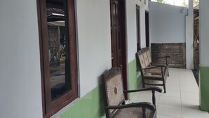 Un pasillo con suelo de baldosas, puertas de madera y sillas de mimbre.