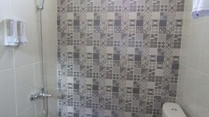 Un baño con ducha, inodoro y azulejos estampados.