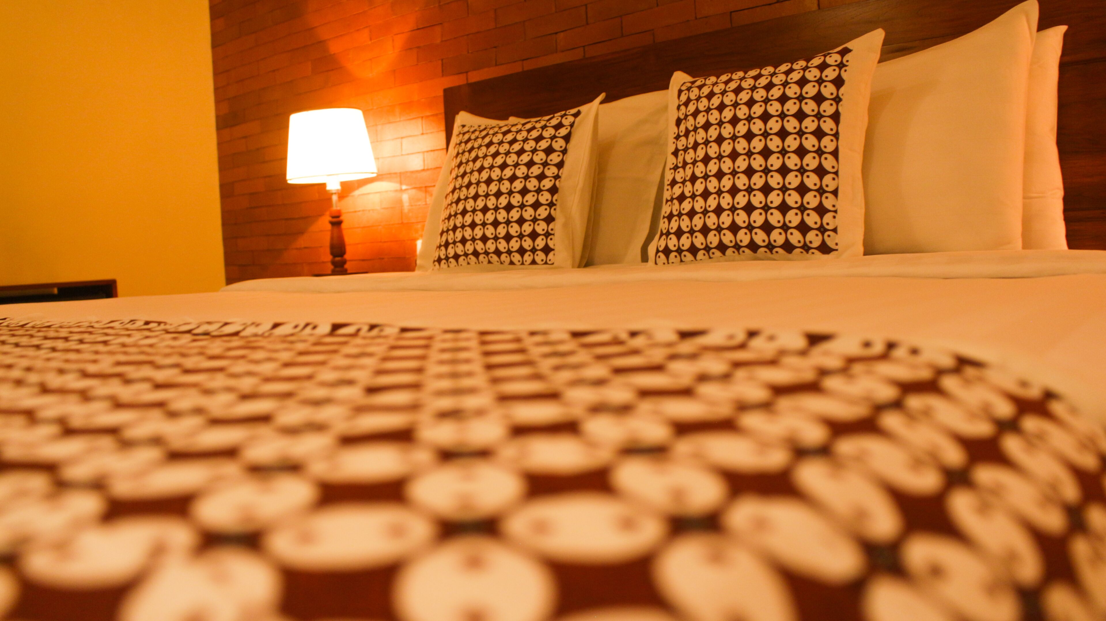 A bed with patterned pillows and a circular rug.