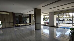 Un vestíbulo amplio con piso pulido, una zona de estar y ventanas grandes que dan vista a coches estacionados afuera.