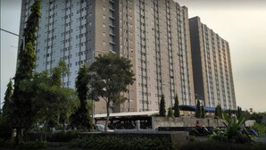 Un edificio de gran altura con varios pisos, rodeado de vegetación y un paseo techado.