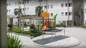 Un patio de recreo con toboganes y estructuras para escalar, rodeado de edificios.