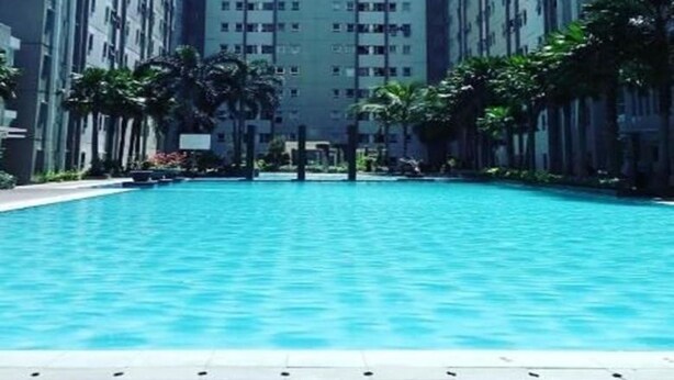 Una piscina rodeada de edificios residenciales altos con cielo despejado.