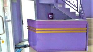 A purple reception desk with a Hello Kitty plush toy on it, located near a staircase.