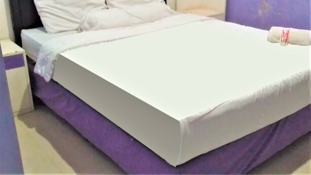 A bed with white bedding, a purple mattress cover, and a pillow.