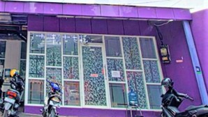 Un edificio morado con amplias ventanas y una motocicleta estacionada al frente.
