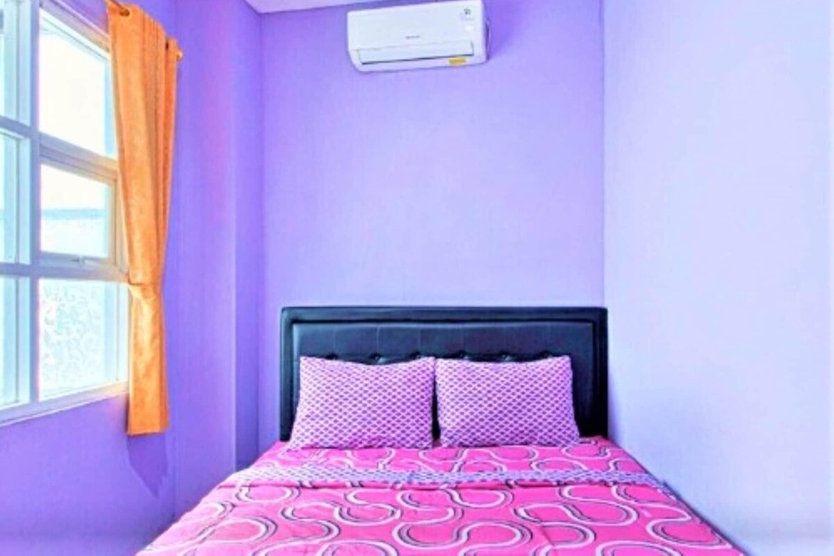 Una habitación con una cama, una ventana con cortinas y un equipo de aire acondicionado en la pared.
