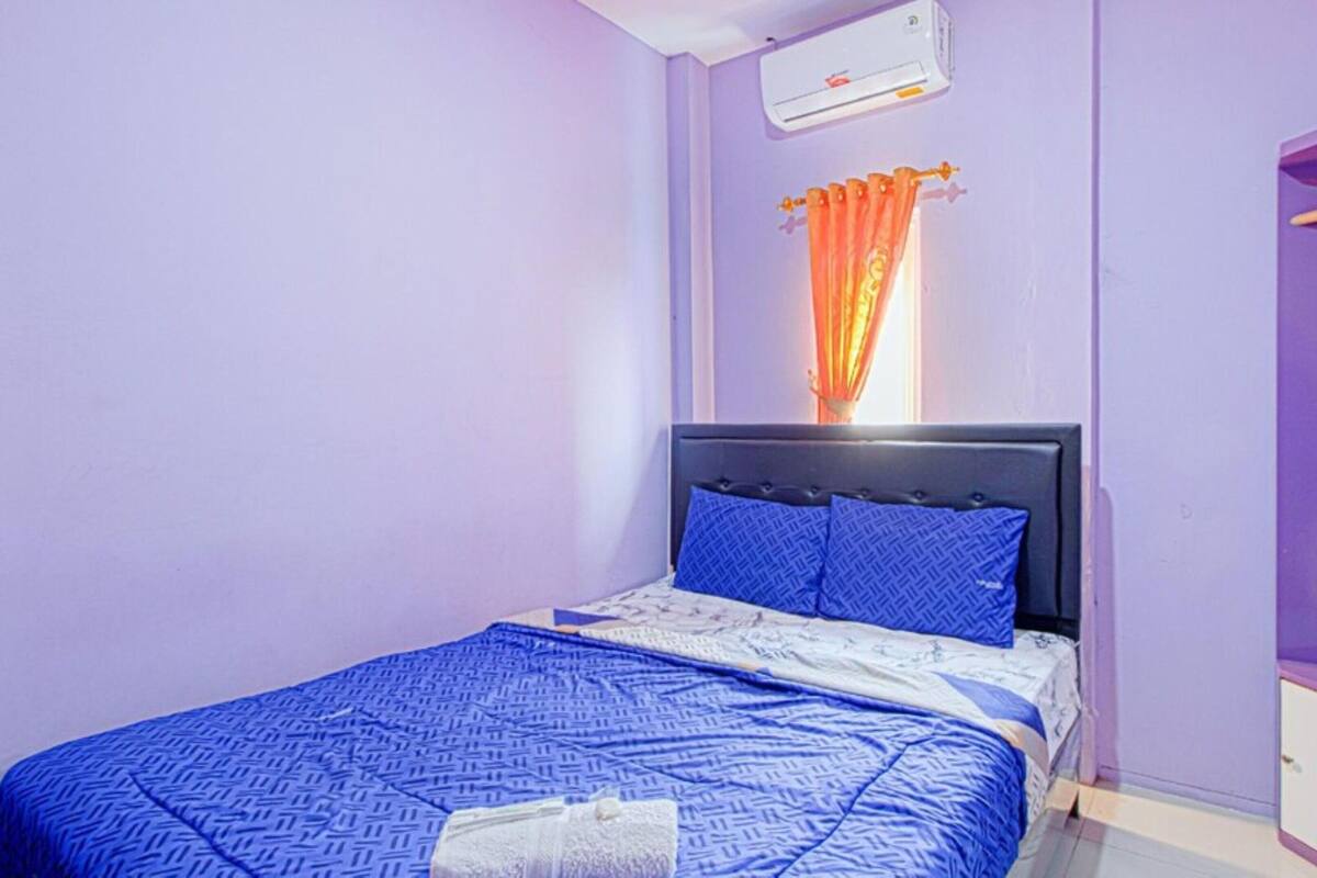 A bedroom with a bed, a wardrobe, and an air conditioning unit.