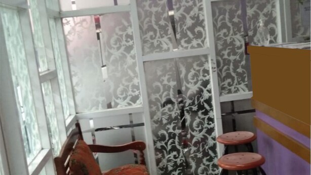 Una habitación con una silla de madera, un taburete de bar y un separador decorativo con diseños estampados.