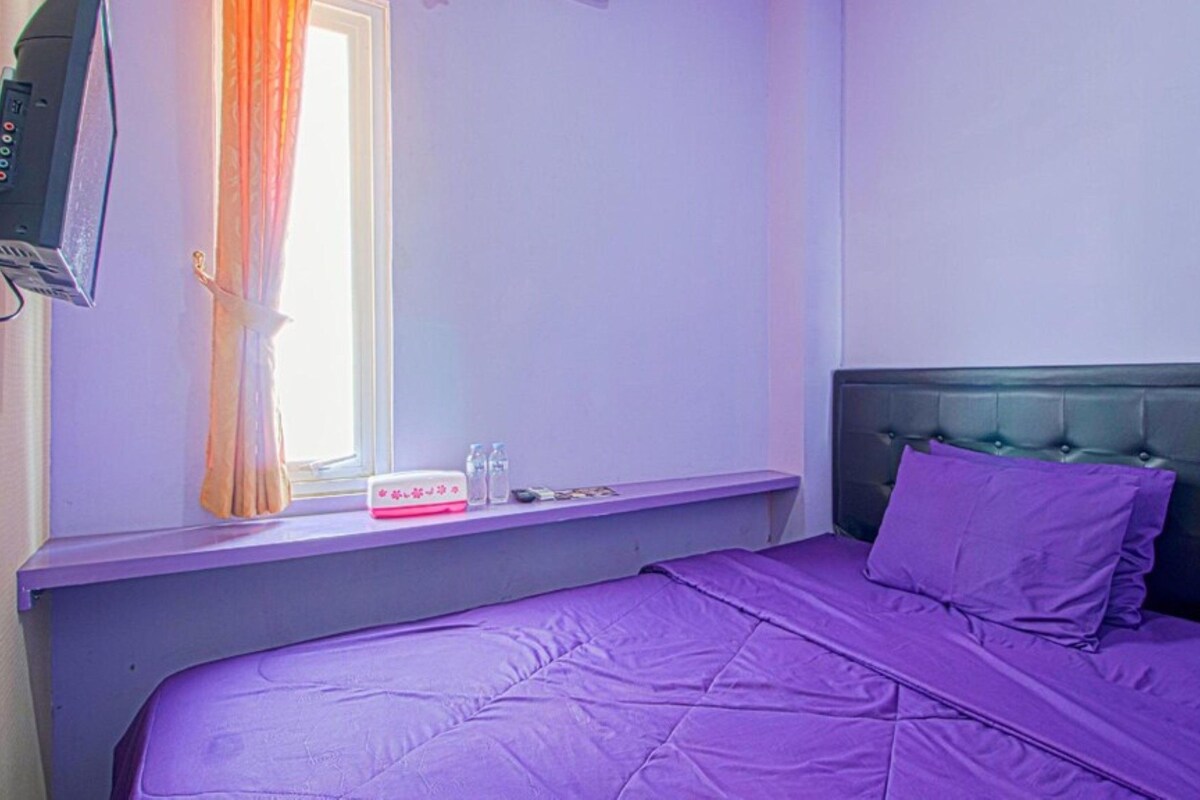 A room with a bed, a window with curtains, a bedside table, and a television.