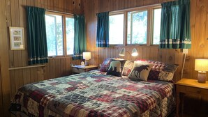 A wooden-paneled bedroom with a large bed, two bedside lamps, and curtains. - WestWind Georgian Bay Muskoka Cottage Retreat Private Access (Sleeps Max 8) (MacTier)