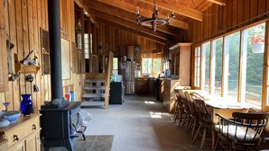 A wooden cabin interior with a kitchen, dining area, and a staircase leading to a loft. - WestWind Georgian Bay Muskoka Cottage Retreat Private Access (Sleeps Max 8) (MacTier)