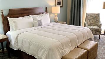 A large bed with a wooden headboard, a bedside table, a chair, and a patterned carpet.