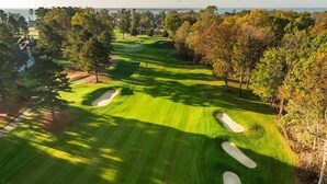 Un campo de golf con búnkeres de arena, árboles y una vista despejada del océano.