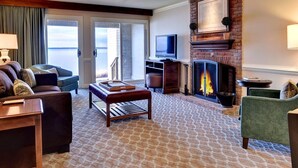 Amplia sala de estar con chimenea, televisor y vistas al exterior.