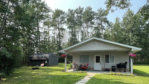 A single-story house with a covered porch, a small patio, and a lawn. - Guest House at Parkland Beach, Gull Lake (Ponoka County)