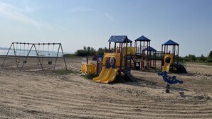 A playground with swings and slides on a sandy beach with a clear sky. - Guest House at Parkland Beach, Gull Lake (Ponoka County)