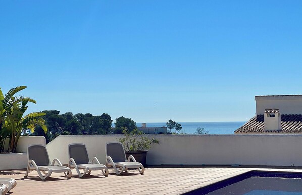 Una terraza en la azotea con sillones de descanso, piscina y vistas al mar.