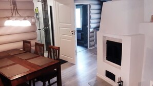 A log cabin interior with a dining area, a fireplace, and a view into the living space.