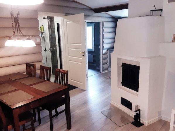 A log cabin interior with a dining area, a fireplace, and a shower.