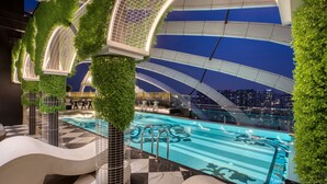 Une piscine intérieure moderne offrant une vue sur le paysage urbain, entourée de verdure et agrémentée d’éléments architecturaux originaux.