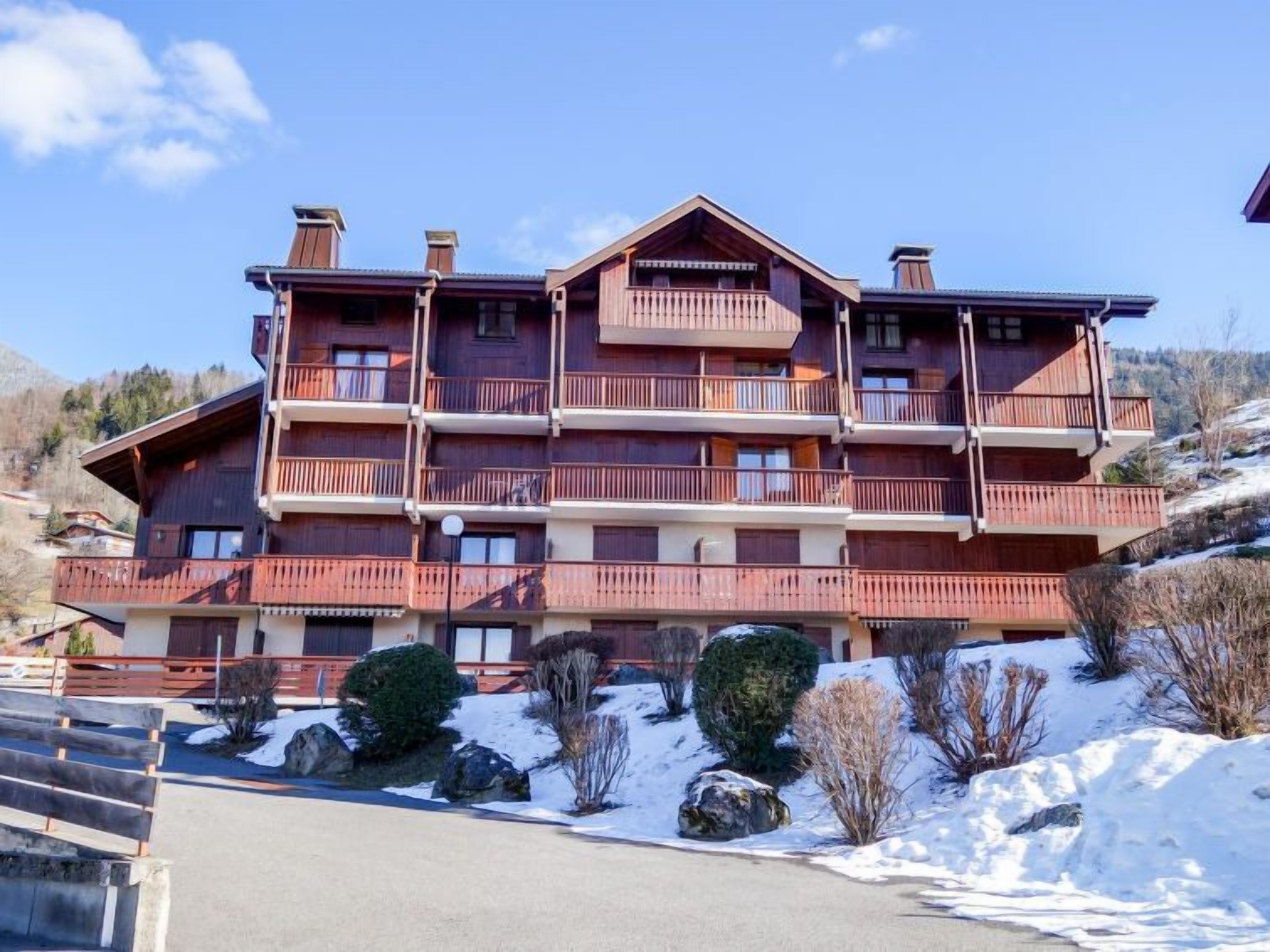 Un edificio de madera de varios pisos con balcones, rodeado de nieve y árboles.