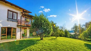 A two-story house with a balcony, a well-maintained lawn, and a clear sky. - Villa La Verbanina Private Garden, Ghiffa, Italy (Ghiffa)