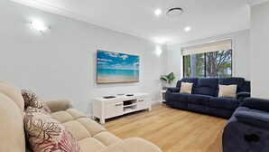Una sala de estar moderna con un televisor grande, un sofá azul y un sofá beige.