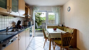 A kitchen with a sink, stove, and dining area with chairs and a table.