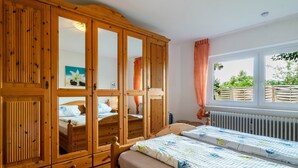 A bedroom with wooden furniture, a window with a view, and a radiator.