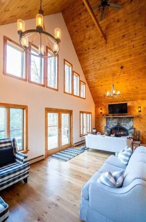 Cozy living area with a high ceiling, fireplace, and large window.