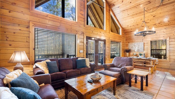 A cozy cabin interior with a wooden interior, a fireplace, and a dining area. - Peaceful Pines: Hot Tub/Playground/Games + Eateries/Brewery/Hiking/Lake~3mi! (Broken Bow)
