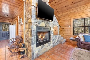 Une cheminée en pierre avec un téléviseur fixé au-dessus, un intérieur en bois et une pancarte d'accueil rustique.