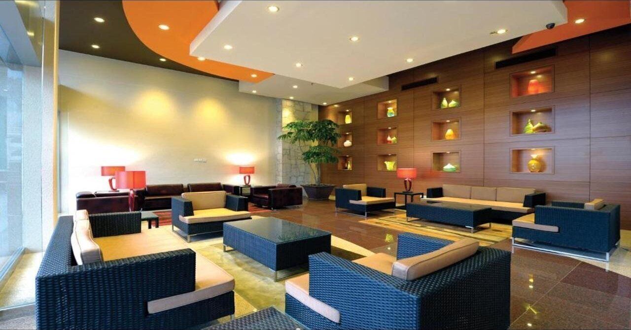 A modern lobby with seating areas, a large plant, and wall-mounted lighting.