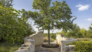 A stone structure with a tree in the center, surrounded by a stone pathway and a flower bed.
