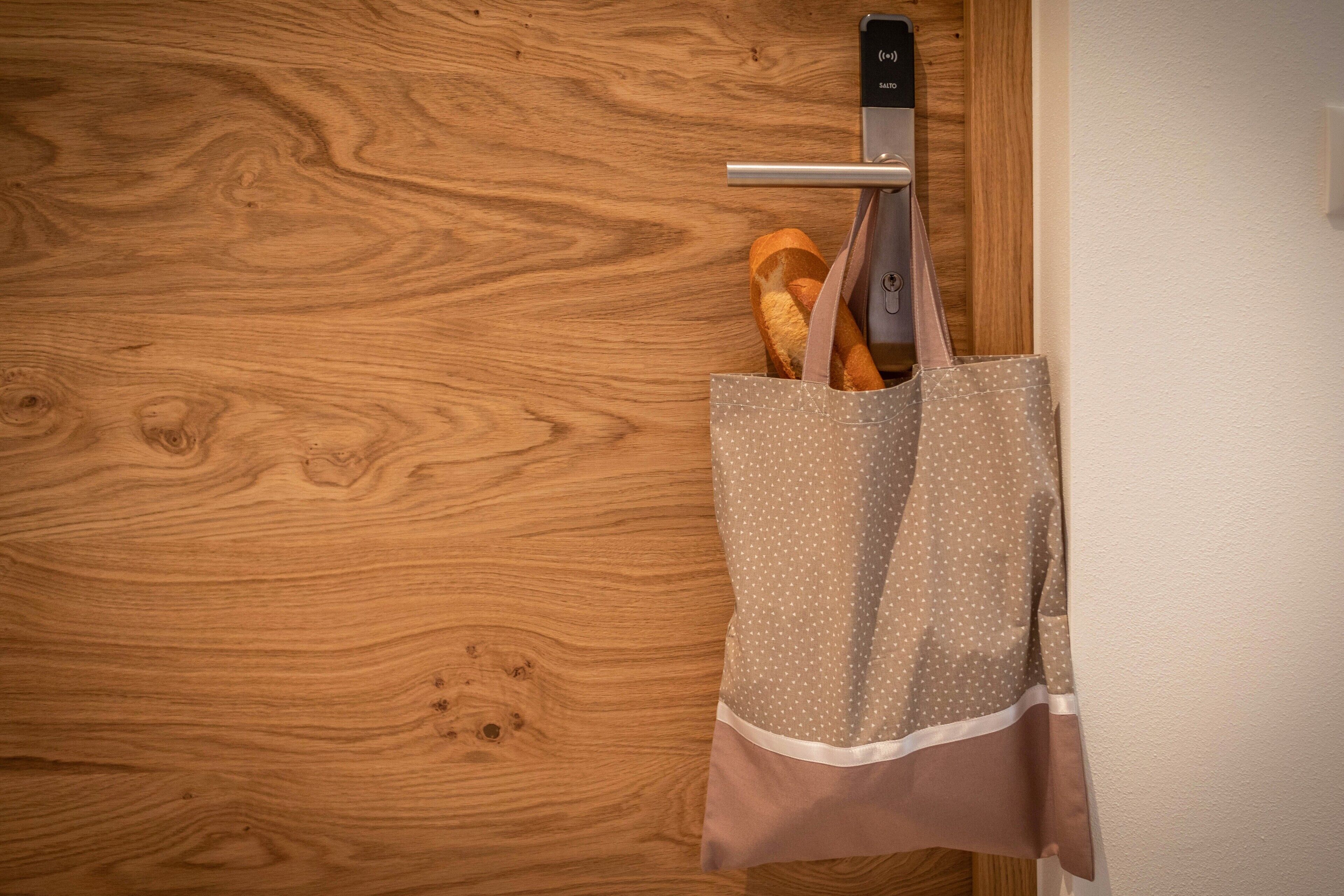 A wooden door with a metal handle and a polka-dotted bag hanging on it.