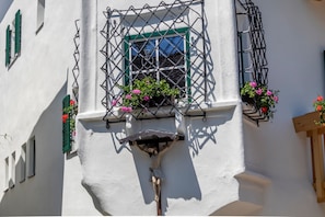 Un bâtiment orné d’un crucifix, doté de volets verts et de jardinières fleuries.