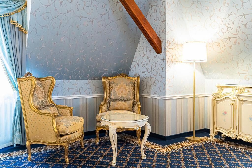 Una habitación con dos sillones decorados, una mesita y una lámpara.