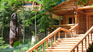 A wooden cabin with a staircase leading to a balcony.