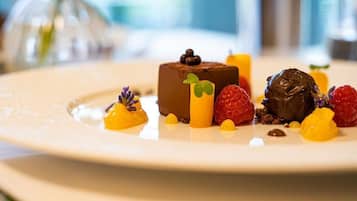 A dessert plate with a chocolate mousse, raspberries, and yellow fruit pieces.