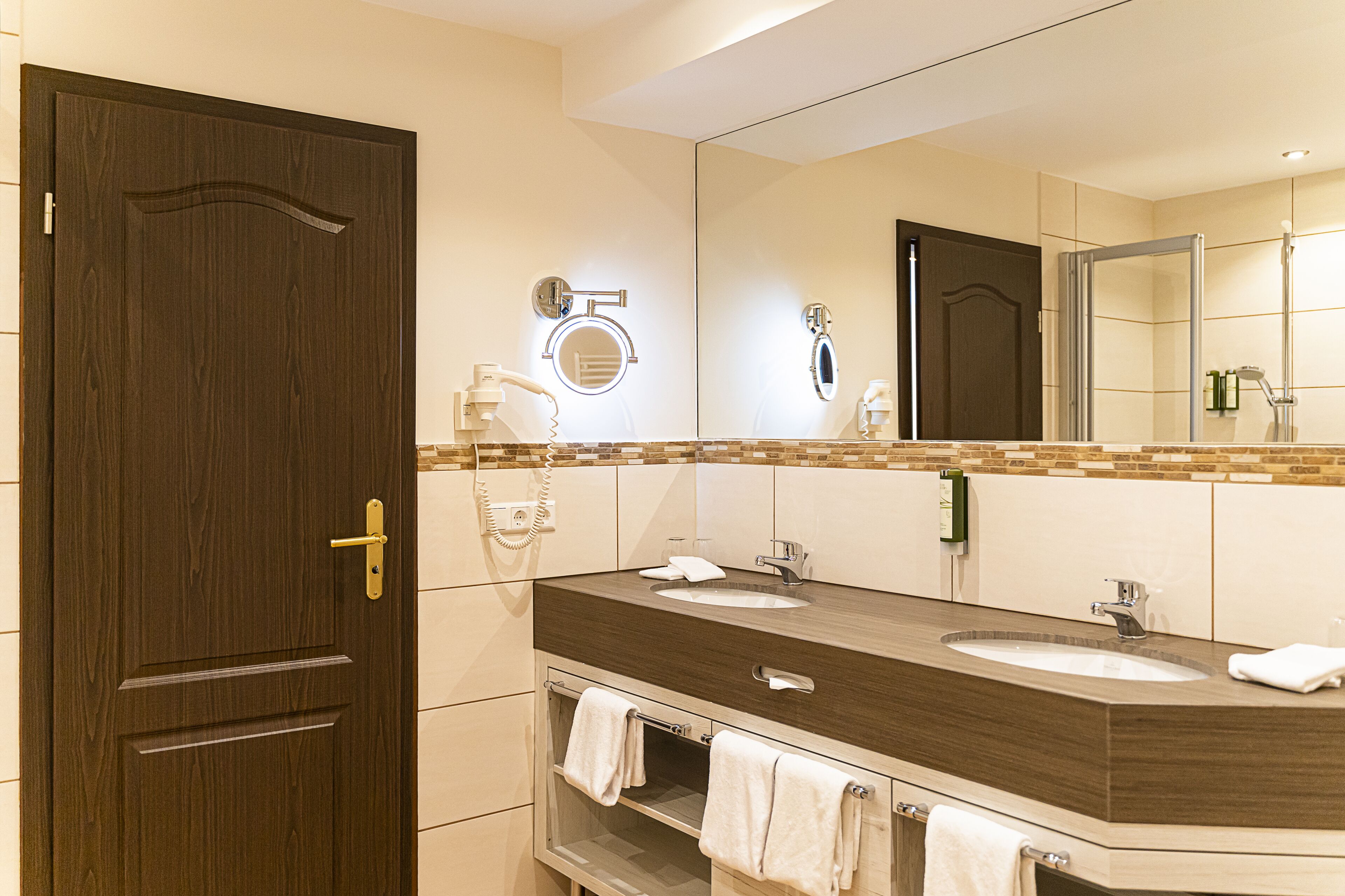 Un bagno moderno con due lavabi, uno specchio grande e una porta in legno.