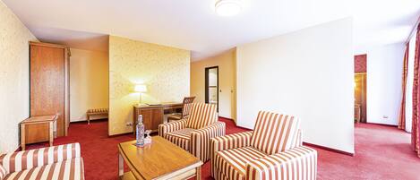 Una habitación de hotel con sofás a rayas, una mesa de madera, una lámpara y un escritorio pequeño.