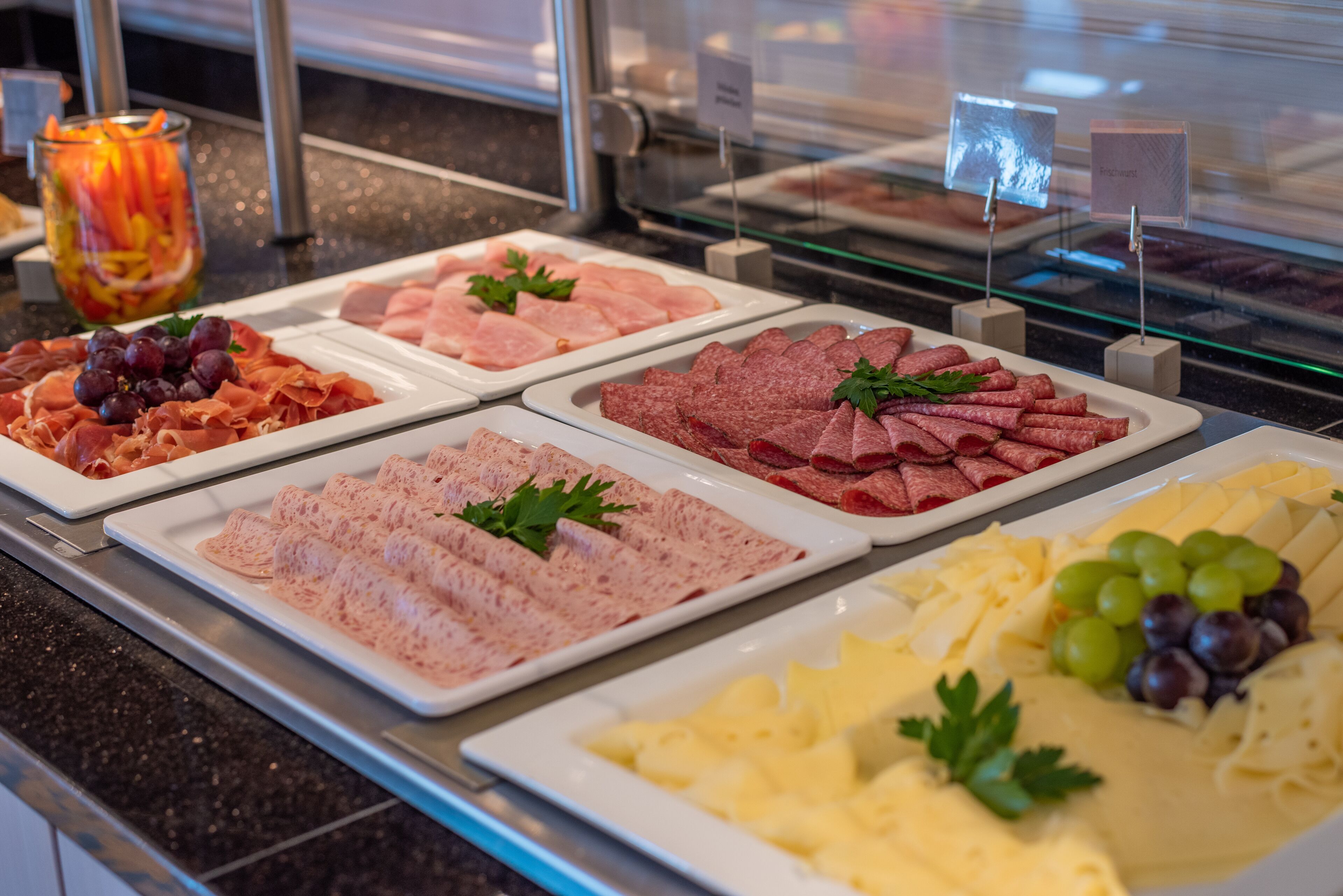 A buffet with various food items including meats, cheeses, and fruits.