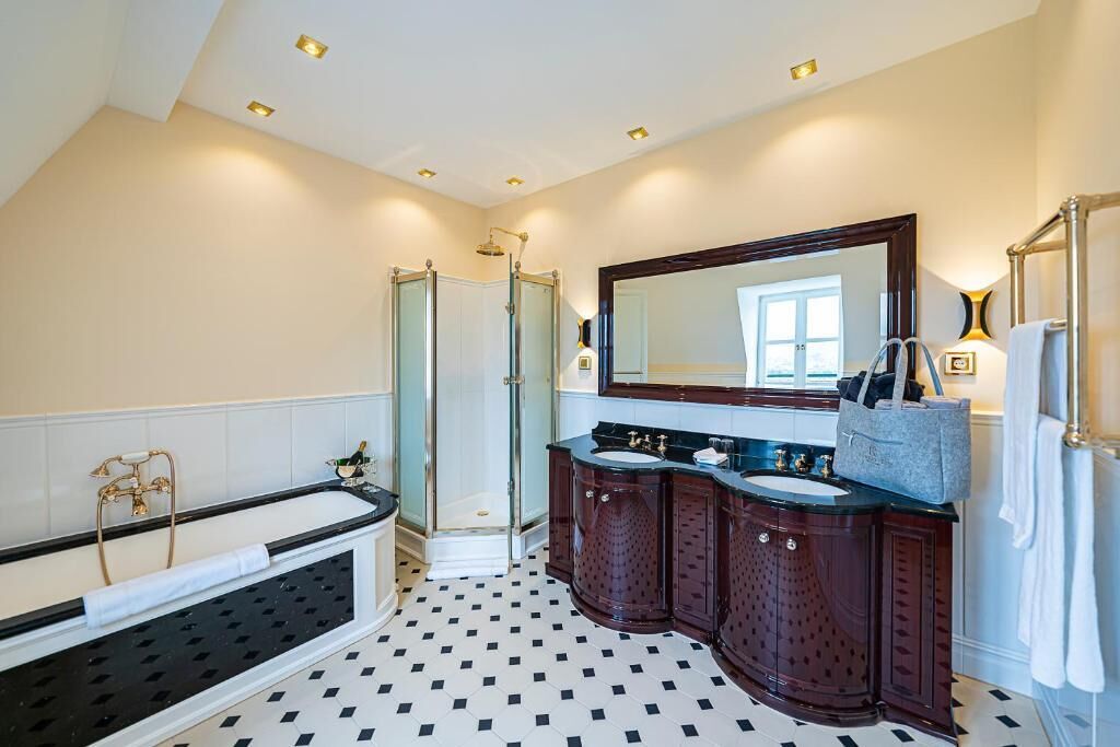 A bathroom with a bathtub, double sink vanity, and a walk-in shower.