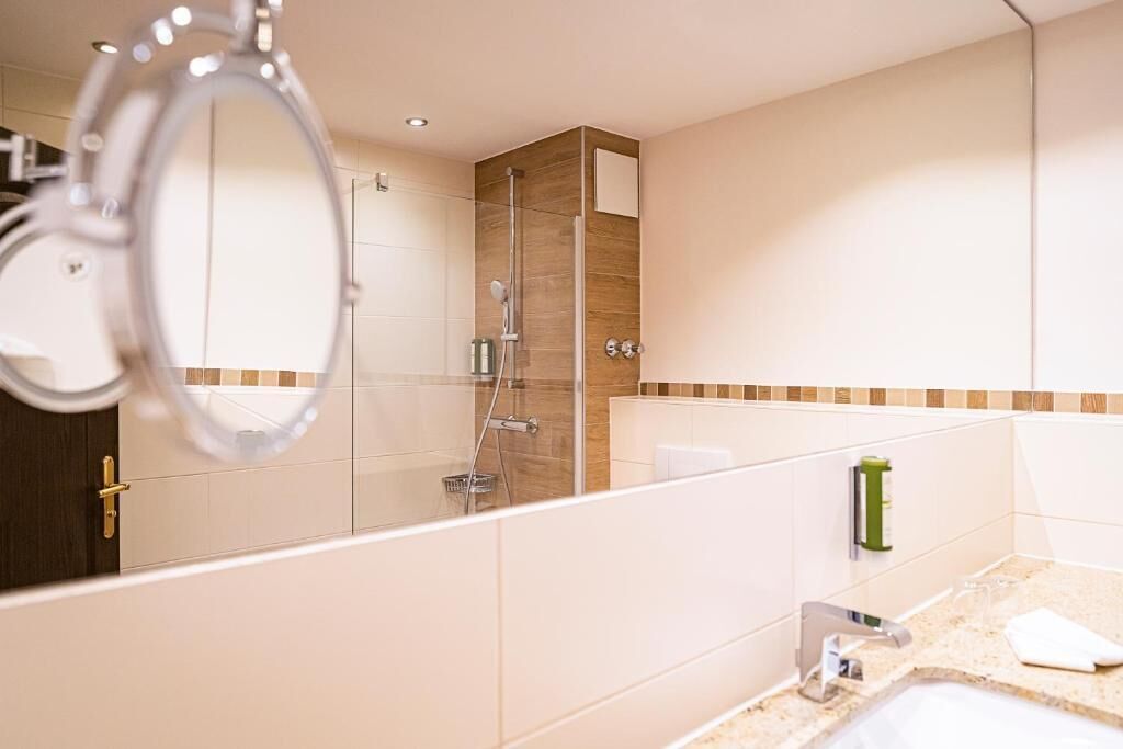 A modern bathroom with a glass shower enclosure, a sink, and a mirror.