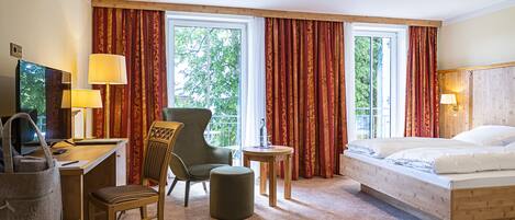 A hotel room with a bed, desk, chair, and a small table.