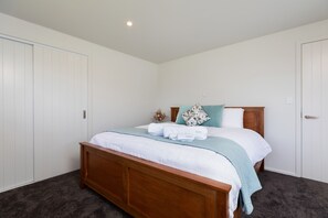 A bedroom with a wooden bed, white walls, and a dark carpet.