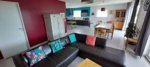 A living room with a black leather sofa, a wooden coffee table, and a red wall. - Villa with pool, 10 persons, fully equipped with calm, clear view (Joyeuse)
