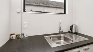 A small kitchenette with a stainless steel sink, a kettle, and a window above the sink. - Auckland Akl Airport Motel (Auckland)